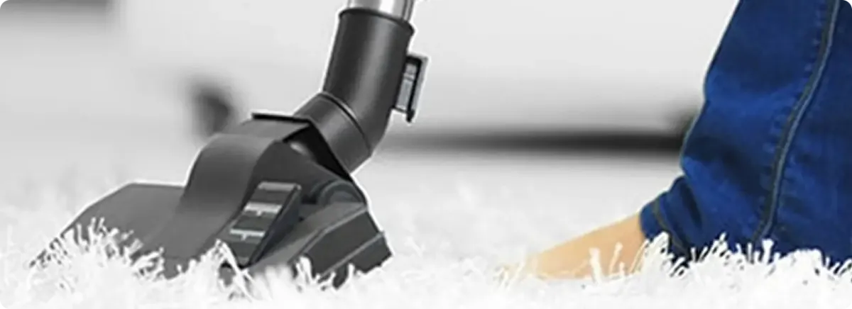 Close-up of a professional vacuuming a white carpet in Urbandale.